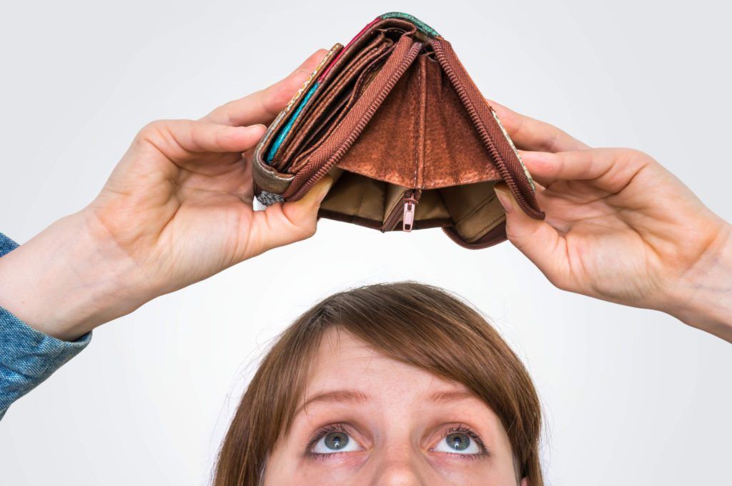 Why is my electricity bill so high? Picture of a woman holding an empty wallet upside down looking for money to fall out.