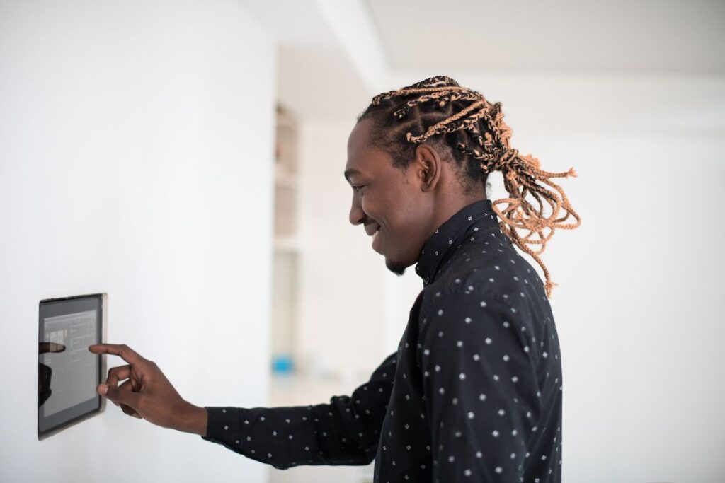 Best home energy monitors on the market. Photo of a man using a smart home device to manage energy usage in home.