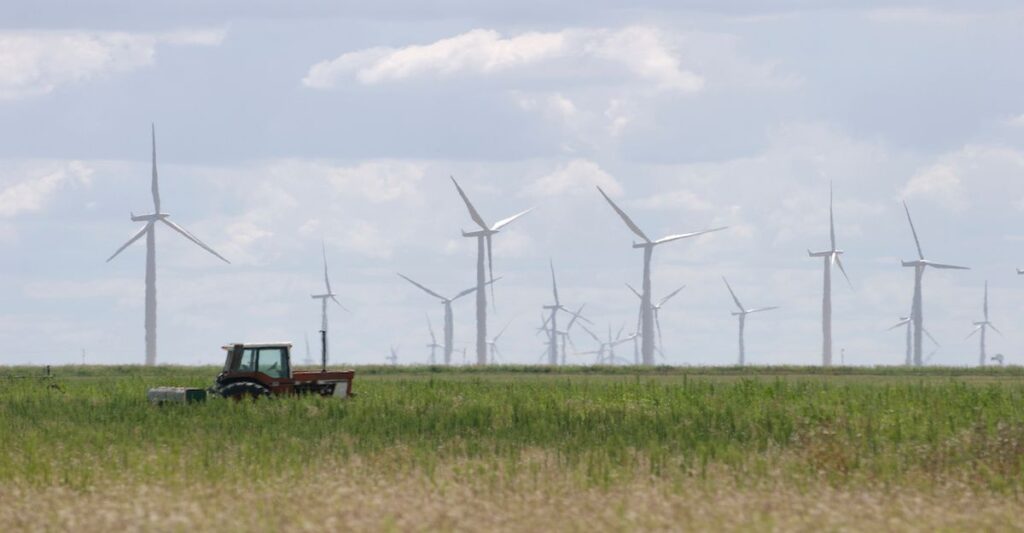 We share when is the best time to shop for electricity in Texas. Photo of a wind farm set in a field with a parked tractor in Texas.