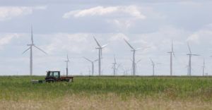 We share when is the best time to shop for electricity in Texas. Photo of a wind farm set in a field with a parked tractor in Texas.