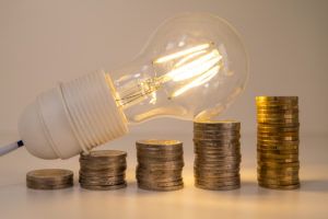 Eversource and United Illuminating have both approved rates increases in CT effective September 2024. Photo of light bulb laying on stacks of coins.